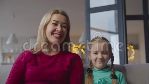 快乐的妈妈和可爱的女孩在家看电视节目视频的预览图