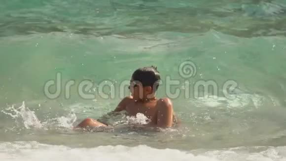 海浪的海浪覆盖着一个晒黑了的男孩戴着泳镜视频的预览图