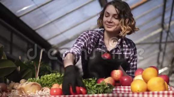 一位戴着黑色手套在农场市场上摆放有机食品的美丽微笑的女农民的低角度视角绿色鸡蛋视频的预览图