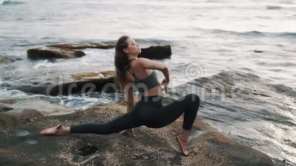 年轻女子在海滩上做伸展运动背景是海洋动作缓慢视频的预览图
