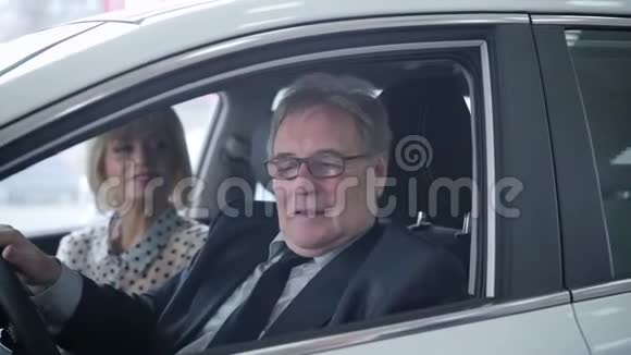 幸福的老白种人家庭从新车上拿车钥匙坐在里面的肖像启动引擎的人视频的预览图