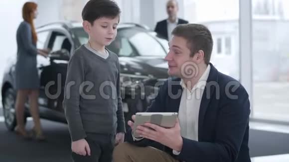积极的年轻白种人汽车经销商的肖像在他的父母选择新的黑人男孩时娱乐小男孩视频的预览图