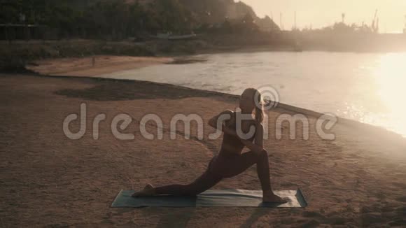 女孩的侧角和眼镜蛇瑜伽姿势在海滩上视频的预览图