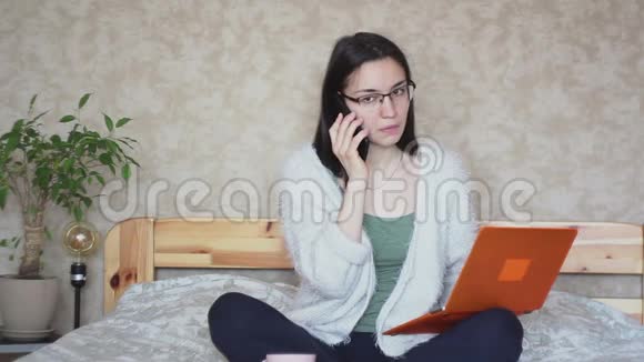 一个年轻迷人的女孩正在用手机和电脑上的数据进行比较视频的预览图