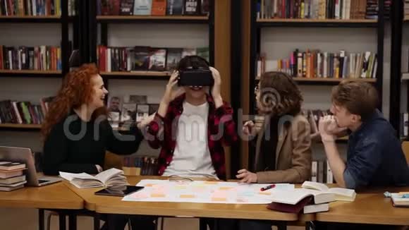 穿格子衬衫的男孩在同学间的大学图书馆里戴着虚拟现实眼镜的概念视频的预览图