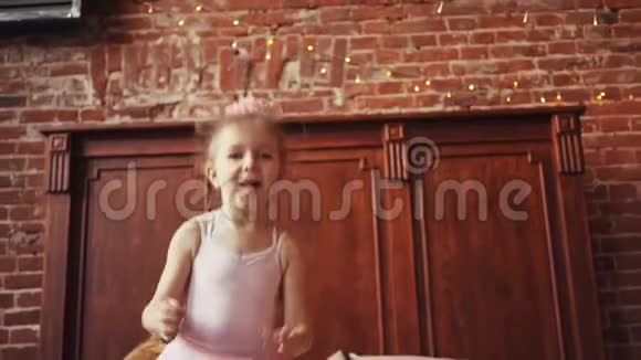 可爱的金发女孩在床上跳跃童年快乐和快乐慢动作对斯泰迪达姆的射击视频的预览图