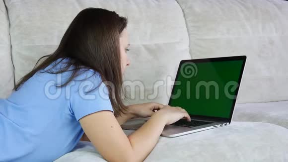 女人用笔记本电脑工作场所在家里用绿色屏幕视频的预览图