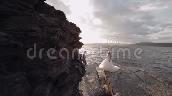 新郎向新娘伸出手来海边的新婚夫妇视频的预览图