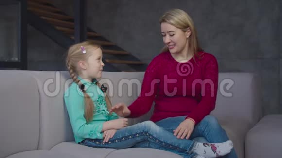 在休闲的时候爱照顾的妈妈和女孩在沙发上分享视频的预览图