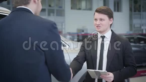 褐发白种人蓝眼睛交易员穿着商务服的画像摇着客户的手和谈话年轻汽车经销商视频的预览图