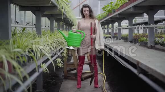 布鲁内特白种人女士穿着红色大腿高靴拿着水缸和铲子美丽的黑发女人站在视频的预览图