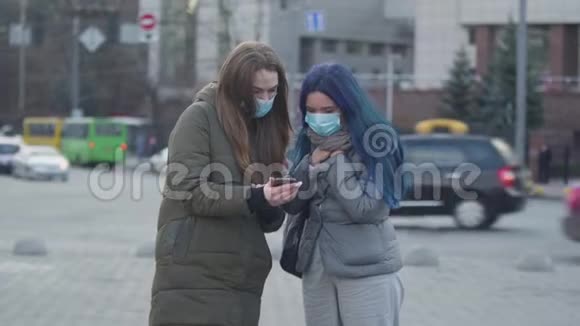 布吕内特女士戴着防护面罩在智能手机上向朋友展示有关冠状病毒的最新消息并以女孩的身份离开视频的预览图