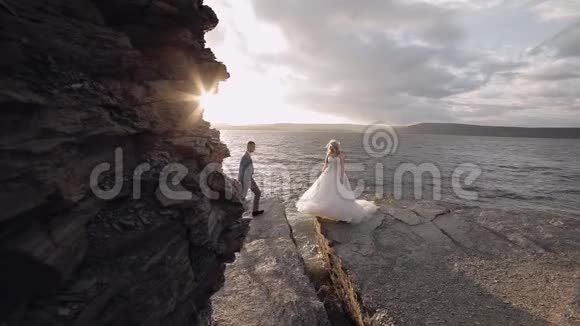 新郎向新娘伸出手来海边的新婚夫妇视频的预览图