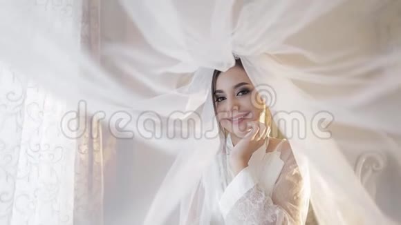 美丽可爱的新娘在面纱下穿着睡衣婚礼日视频的预览图