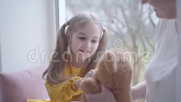 可爱的小女孩和泰迪熊玩和面目全非的祖母说话的肖像白种人视频的预览图