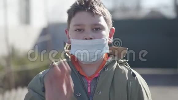 小白种人黑发男孩戴着面具对着镜头挥手的肖像棕色眼睛的可爱孩子戴着防护用品视频的预览图