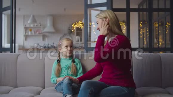 可爱的妈妈和小女儿在沙发上亲热视频的预览图
