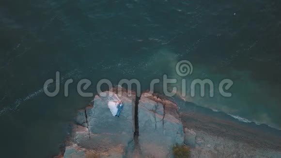 新婚夫妇正躺在海边的山腰上空中射击视频的预览图