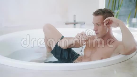 帅哥坐在现代浴缸里喝香槟视频的预览图