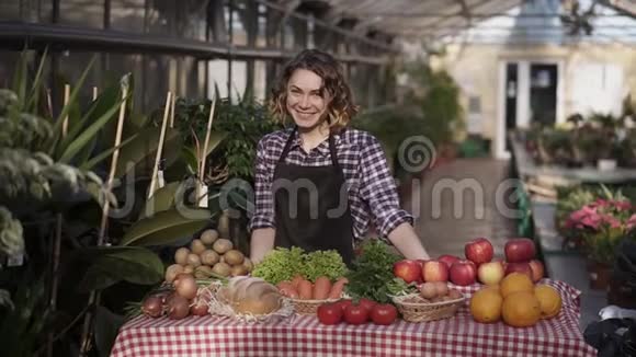 一幅美丽的女农民在农贸市场卖有机食品的画像微笑着看着站在室内的摄像机视频的预览图