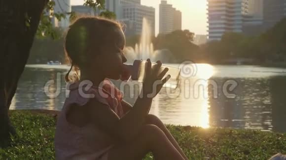 公园的儿童饮用水背景是湖和摩天大楼视频的预览图