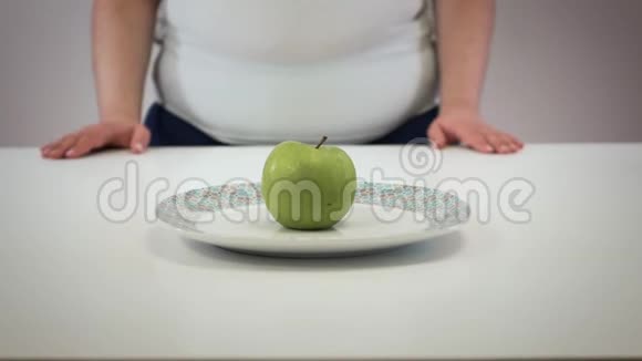 女性白种人的手拿着苹果盘子腹部有褶皱肥胖的年轻女性超重问题视频的预览图