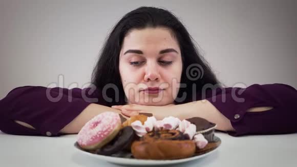 镜头逼近让坐在糖果面前舔嘴唇的白人胖女人心烦意乱奥比斯女孩看着美味视频的预览图