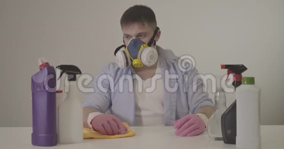 成人白种人呼吸器喷洒清洁剂和室内擦桌的肖像年轻小伙子视频的预览图