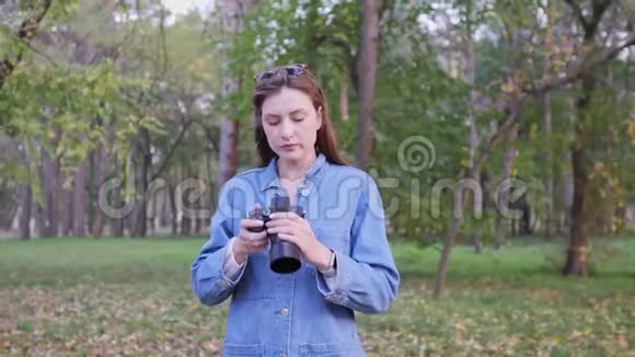一位年轻美丽的女性自由职业者在一个秋天公园里拿着相机的肖像女孩为社交网络拍照视频的预览图