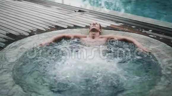 性感男人放松享受户外按摩浴缸慢动作视频的预览图
