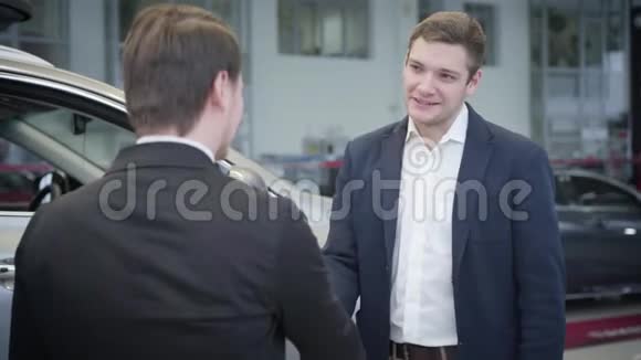 感恩白种人在汽车经销商手中握手的肖像英俊的年轻商人视频的预览图