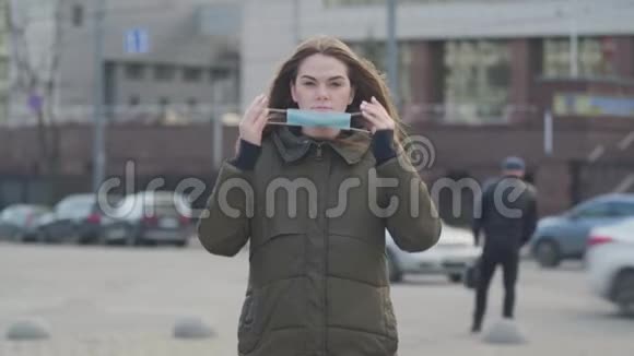 中镜头的年轻黑发女子站在城市街道上戴上防护面具焦虑的女人保护视频的预览图