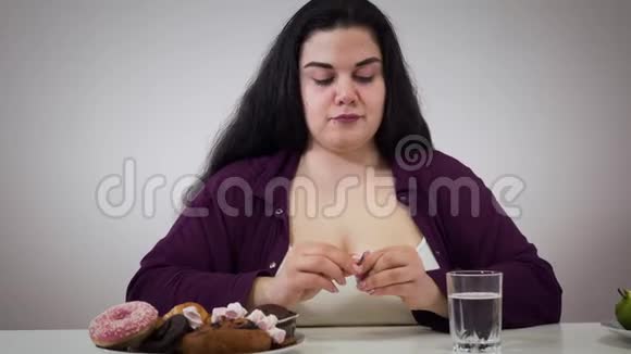 自律丰满的白种人妇女服用代谢药丸移动盘子与糕点远离和微笑肥胖女孩视频的预览图