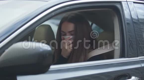 疲惫的女人坐在车里关上车窗咳嗽得厉害年轻女子穿着视频的预览图