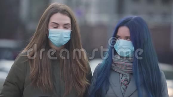 两个戴着防护面具的年轻女人互相看着签名和看着相机女性朋友的特写视频的预览图