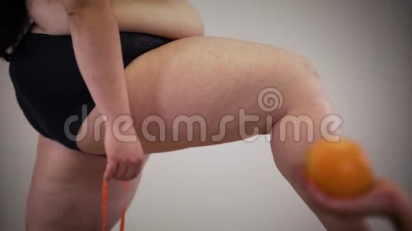 白种人不可辨认的女性用卷尺测量腿部女性手拿着橙色在前景视频的预览图