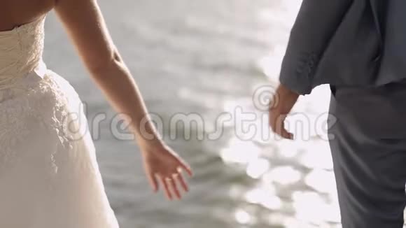 新婚夫妇站在海边他们互相握手新郎和新娘视频的预览图