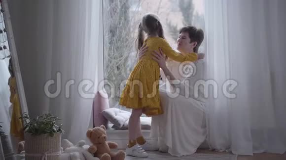 优雅的穿着黄色衣服的小女孩在穿着白色衣服的祖母耳边低语秘密快乐的白人孩子视频的预览图