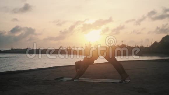 女孩向上向下狗瑜伽姿势在垫子在日出视频的预览图