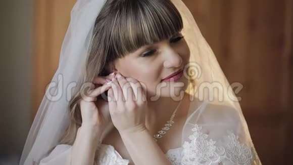 穿着婚纱戴面纱戴耳环的美丽可爱的新娘视频的预览图