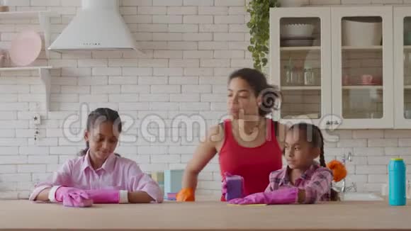 非洲妈妈和女孩用洗涤剂清洗桌子视频的预览图