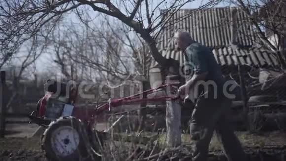 白种人成年男性农民用犁沟造沟的侧面观察老人人工挖土种植马铃薯视频的预览图