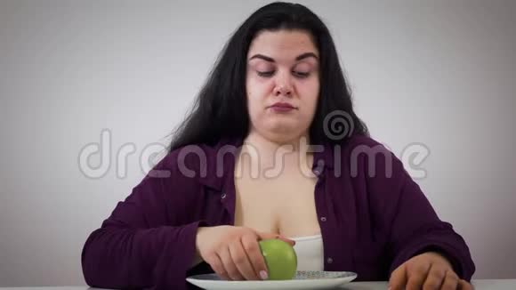 年轻丰满的高加索女人拿苹果签名的肖像讨厌胖女孩吃健康的食物肥胖视频的预览图