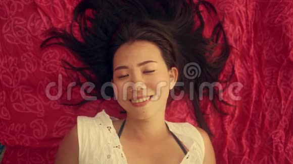 慢镜头高角度拍摄年轻美丽快乐的亚洲女性平躺在莎朗微笑欢快视频的预览图