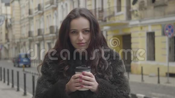 镜头慢慢靠近面对迷人的白人女孩微笑布鲁内特年轻女子在城市大街上摆姿势视频的预览图