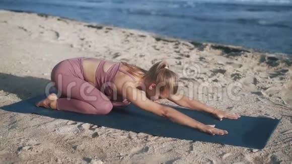 女人在海滩上做瑜伽练习和伸展运动看海洋慢动作视频的预览图
