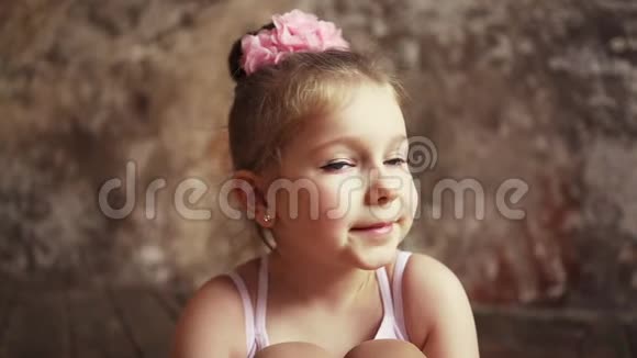 孩子坐在一个空荡荡的房间里微笑金发女郎头上戴着粉红色的蝴蝶结慢动作对斯泰迪达姆的射击视频的预览图