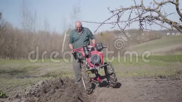 一幅严肃的白人老人带着犁沟沿着乡村花园散步的肖像老农耕肥沃土视频的预览图