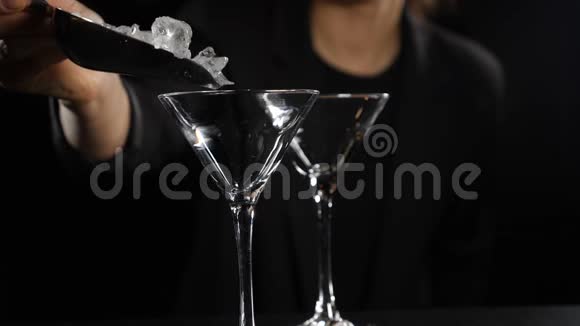 冰块缓慢地落入空玻璃中快关门女调酒师在黑暗的背景下做鸡尾酒全额视频的预览图