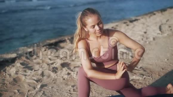 女人在海滩上做瑜伽练习和伸展运动看海洋慢动作视频的预览图